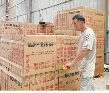 Packing GRG access panels into export cartons with fragile-handling labels, checked before sealing